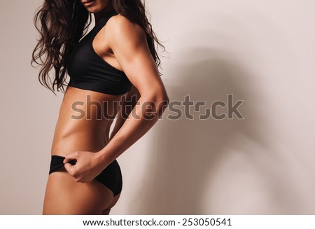Close-up image of fitness female model in sportswear. Fit young woman with muscular body.