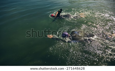 Top view of athletes practicing swimming for triathlon race. Triathlon training in open water.
