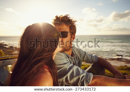 Affectionate young couple kissing at the beach. Loving young couple with sea shore in background. Romantic couple on summer holiday.