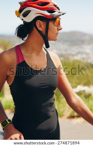 Young sportswoman wearing a cycling helmet looking away. Close-up shot of female cyclist outdoors.