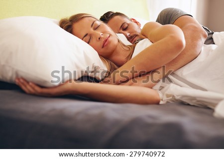 Image of a young couple together sleeping comfortably on the bed. Young man and woman lying asleep.