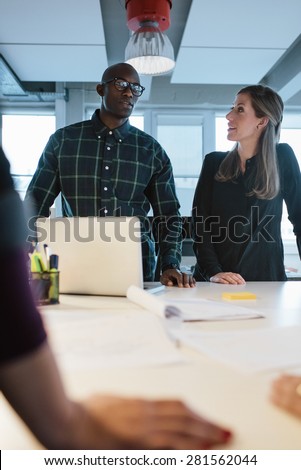 Business people discussing ideas during a meeting around a table in office. Diverse team of young professionals working on new business plan. Multiethnic executives brainstorming during meeting.