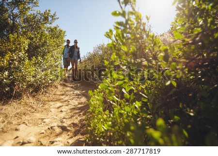 Image of two young people walking downhill. Young couple hiking on mountain on a summer day.