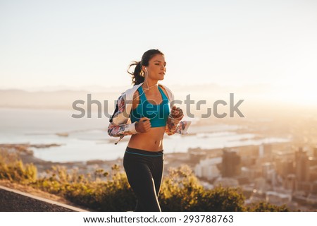 Fit young woman jogging outdoors. Female athlete on morning run with bright light.