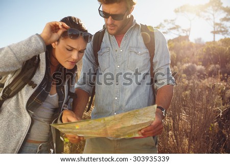 Hikers looking at map. Couple navigating together during travel hike outdoors in countryside.