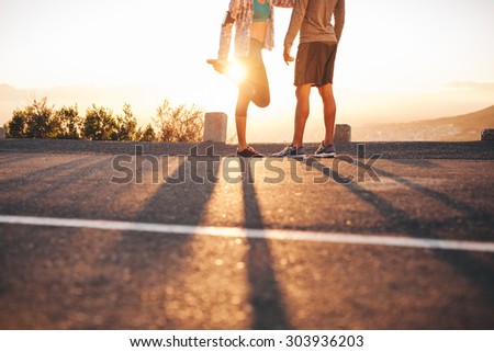 Cropped shot of fit young couple warming up before a run together at sunrise. Young man and woman exercising in morning.