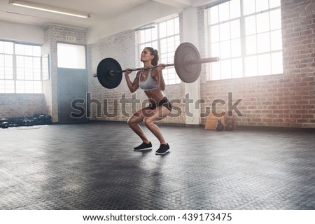 Female bodybuilder doing exercise with a heavy weight bar in gym. Full ...