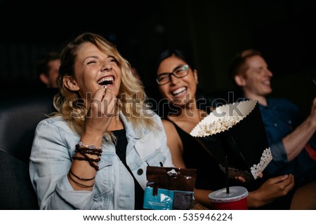 Young woman with friends watching movie in cinema and laughing. Group of people in theater with popcorns and drinks. Imagine de stoc © 