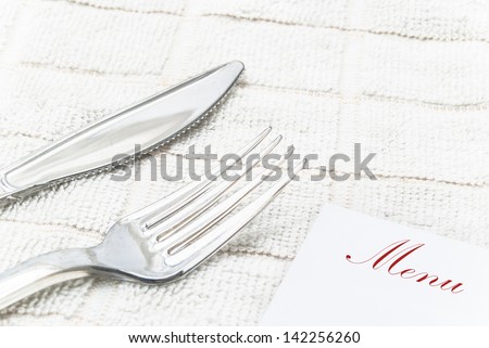 menu card fork and knife on table cloth