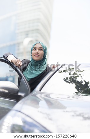Image of Executive women with scarf woman standing near car, bottom angle of view