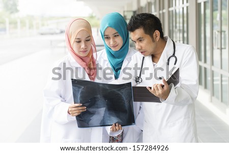 Three  doctors examining a file in in front of hospital