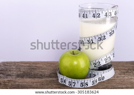 Glass of milk and apple with measurement tape-diet cncept