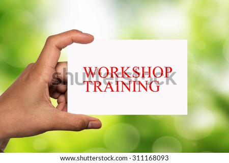 hand holding white card written workshop training over blur background