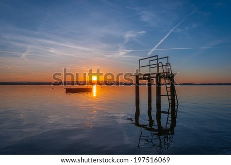 Tower to jump into the water against the backdrop of the setting sun. Reflection of sunlight in the lake. Gorgeous evening sunset colors in the sky and the lake. Lake Zug in central Switzerland.
