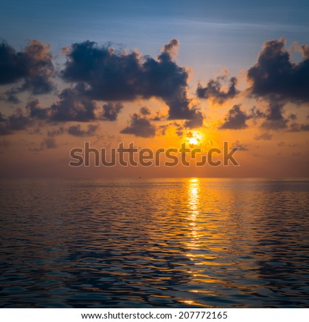 Scenic sunset over the Ocean. Rays of the sun through the clouds. Setting sun painted the sky and ocean in deeply bright  color.