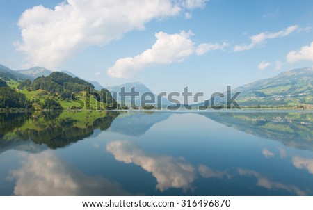 Grand panorama of mountain lake. Clouds and nature are reflected in a mirror surface.