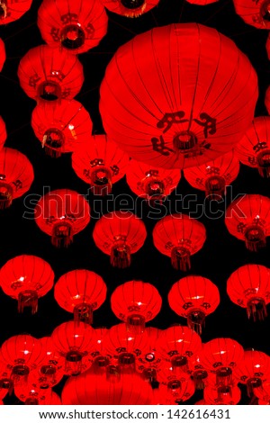 Red, circular Chinese lanterns creating repetitive circular pattern on black background.