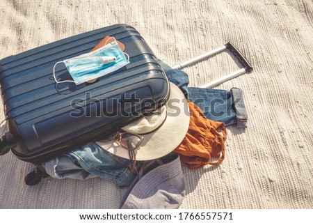 Travel.Todler sits near a suitcase with things and dreams of a vacation traveling after quarantine, lockdown, covid 19. Staycation.local travel.Tourism after the opening of borders, end of quarantine