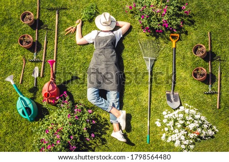Gardening  Gardener Girl Relaxed Lying  Green Grass, Surrounded Gardening Tools With Plants Workplace home among plants  home garden ,agriculture, freelance, work  home, slow life, mood 