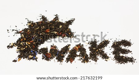 Word wake whith black tea on white background. Black tea  with leaves of flowers fnd other green.