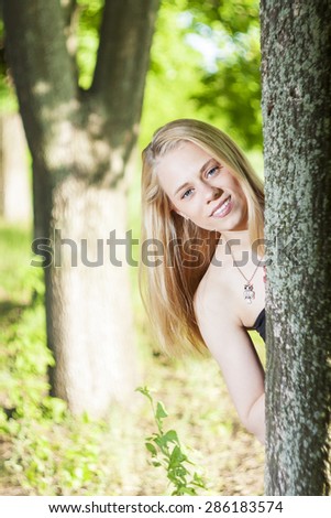 young and beautiful girl withblue eyes smile and posing in the green and trees in the summer