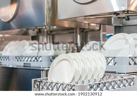 many dish or white plate arranged on basket for cleaning by automatic dishwasher machine in kitchen room restaurant