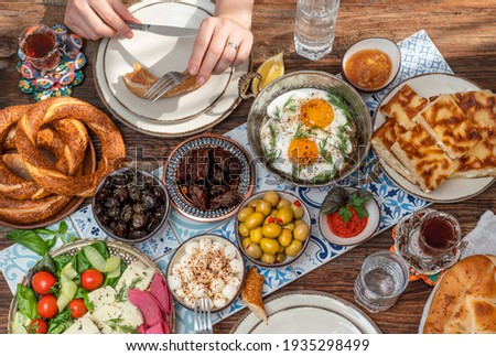 Delicious rich Traditional Turkish breakfast include tomatoes, cucumbers, cheese, butter, eggs, honey, bread, bagels, olives and tea cups. Ramadan Suhoor aka Sahur (morning meal before fasting). 