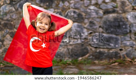 Portrait of happy little kid. Cute baby with Turkish flag t-shirt. Toddler hold Turkish flag in hand. Patriotic holiday. Adorable child celebrates national holidays. Copy space for text.