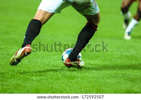 MILAN, ITALY - APRIL 06: Italian professional Serie A soccer match in Milan April 06, 2006. A football player close up kicking the ball with the green pitch on the background.