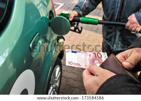 MILAN, ITALY - January 31: Cash payment, with gas station's worker refuels a car in the background are seen in Milan January 31, 2010.