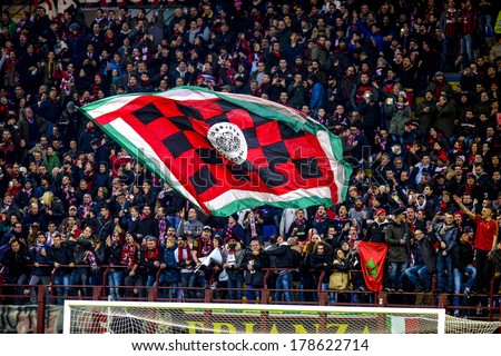 MILAN, ITALY-FEBRUARY 19, 2014: AC Milan fans waving a team flag during a soccer UEFA Champions League match AC Milan vs Athletic Madrid, at  the San Siro stadium.
