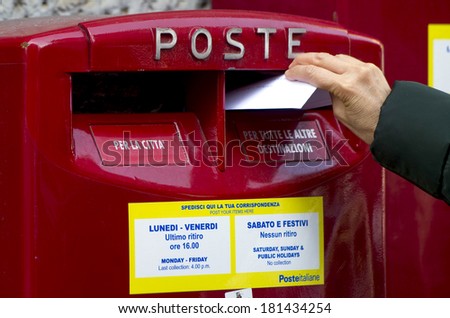 MILAN, ITALY-FEBRUARY 22, 2012: Hand sending a letter in a red mail box outside a post office in Milan.