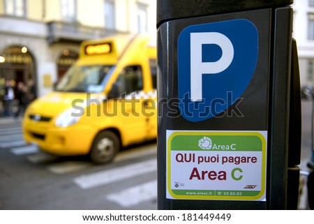 MILAN, ITALY-JANUARY 24, 2012: School bus goes by a parking payment machine, is seen on the street in downtown Milan.