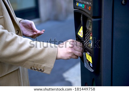 MILAN, ITALY-JANUARY 24, 2012: Man\'s hand insert coin on a parking payment machine on the street, in downtown Milan.