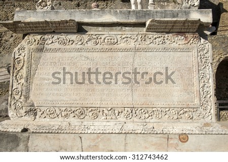ERCOLANO, ITALY-JUNE 24, 2015: Latin words on a stone basement between the ruins of the Roman Emperor\'s town of Ercolano preserved after the eruption of the Vesuvio volcano on 79dc, in Ercolano.