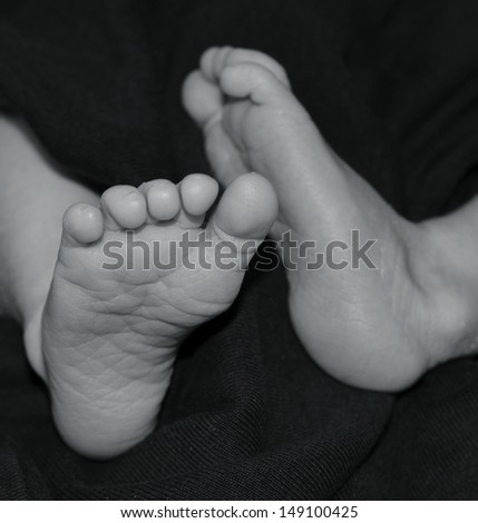 Baby feet in monochrome/ black and white. Clear photo showing new baby feet and toes on black isolated background.