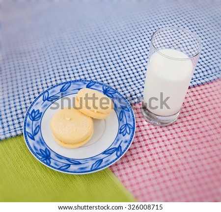 Two melting moment biscuits on a decorated small plate placed on blue, green and red drapery