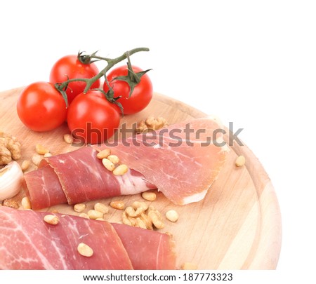 Prosciutto with tomatoes on wooden platter. Whole background.