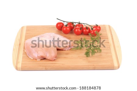 Raw chicken breast with vegetables on wooden platter. White background.