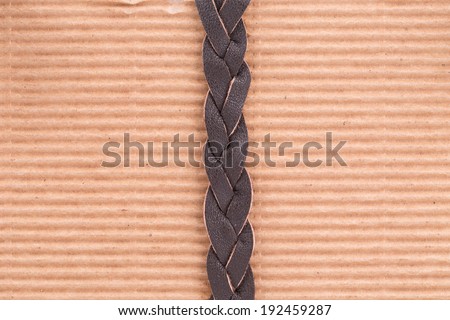 Woven brown leather belt. Whole brown paper background.