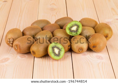 Kiwi in two halves with other kiwis on the back on the wooden desk