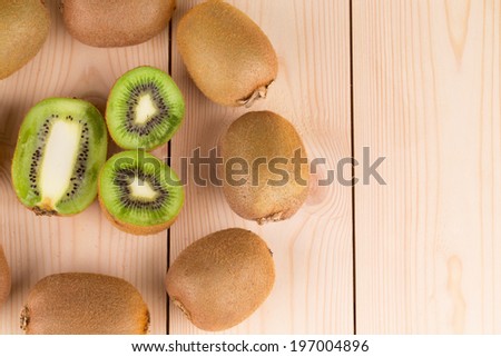 Kiwi in two halves with other kiwis on the back on the wooden desk
