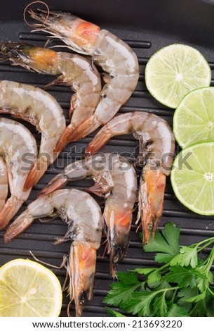 Raw shrimps on pan with lemon. Isolated on a white background.
