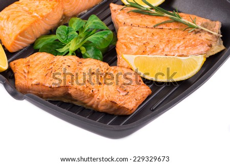 Fried salmon fillet in pan with lemon. Located on the white background.