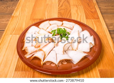 Delicious salted pork fat with parsley. Plate located on wooden table background.