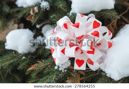 Bow with hearts as a christmas decoration on pine tree branch. Macro. Can be used as a whole background.