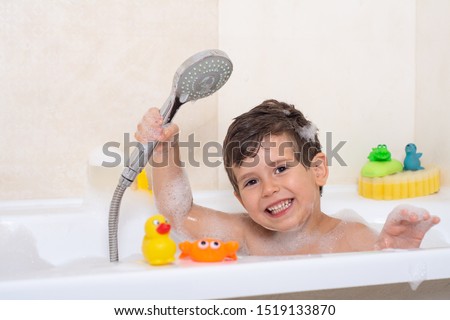 Kid taking bubble bath. Child bathing in bathtub. Little boy playing with water. Rubber duck in foam bath.  商業照片 © 