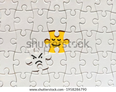 Becoming a better person concept using puzzle. Smiling and good yellow puzzle over bad and angry white puzzle in the middle of frame. Suitable for positivity, becoming better person, patience concept.
