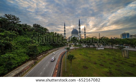 Aerial view of mosque with busy road, light trail. Scenery of sunrise or sunset at Sultan Salahuddin Abd Aziz Shah Mosque, Shah Alam, Malaysia.