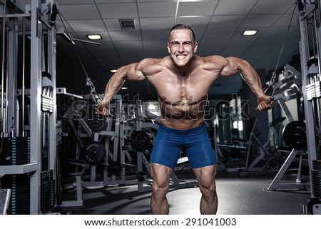 Muscular bodybuilder guy doing exercises workout in gym - breast muscles